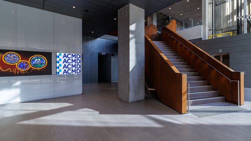 ACMD lobby with staircase, concrete columns and branded wall.