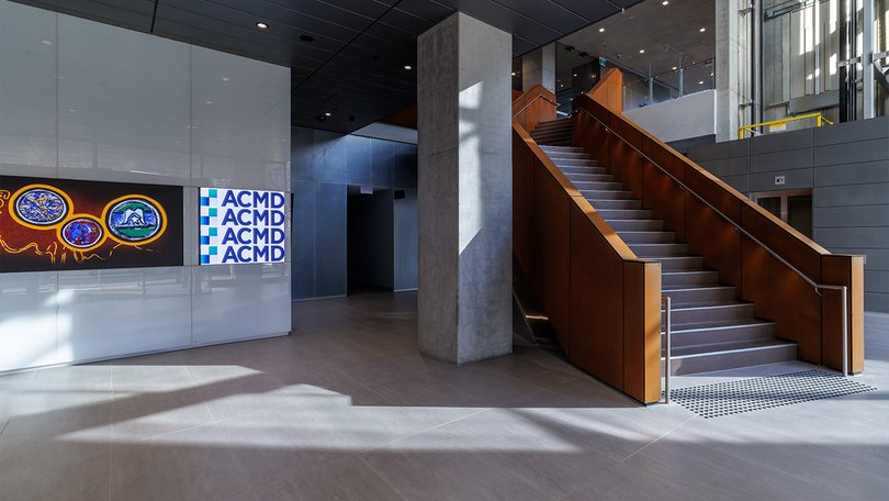 ACMD lobby with staircase, concrete columns and branded wall.
