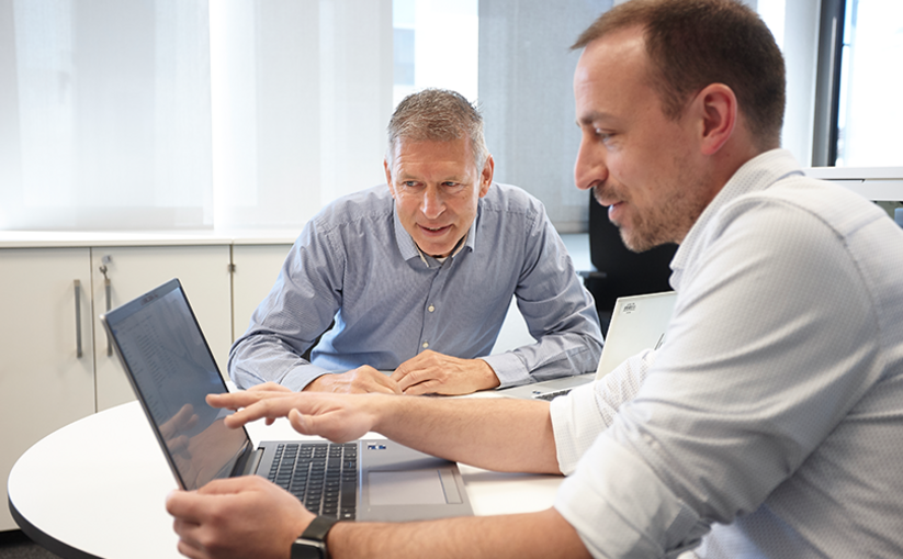 Two men are talking about something on the computer.