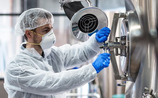 Scientist operating a stainless steel vessel with a nearby extraction unit