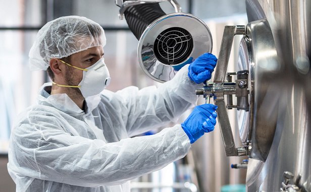 Scientist operating a stainless steel vessel with a nearby extraction unit