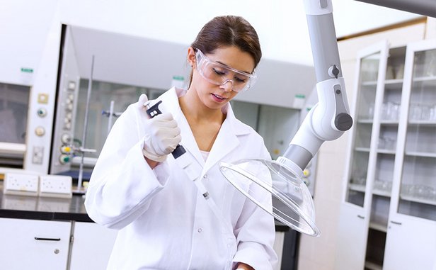 Scientist using a pipette beneath a local extraction arm in a laboratory