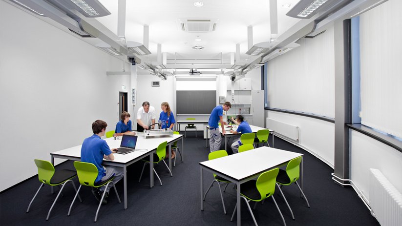 Bright classroom with modular tables and green chairs