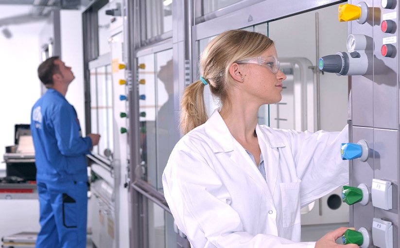 Employee operating control panel while service technician works in the background