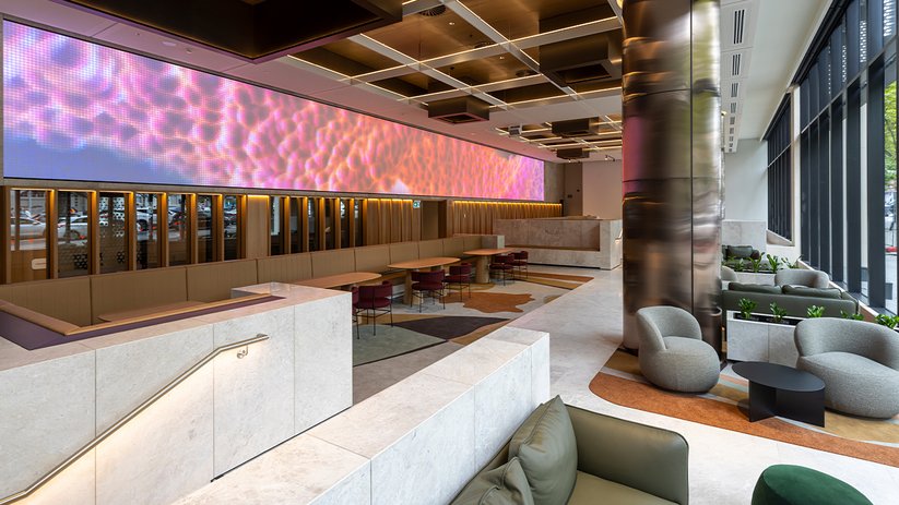 Breakout space at CSL Melbourne with lounge seating and long tables.