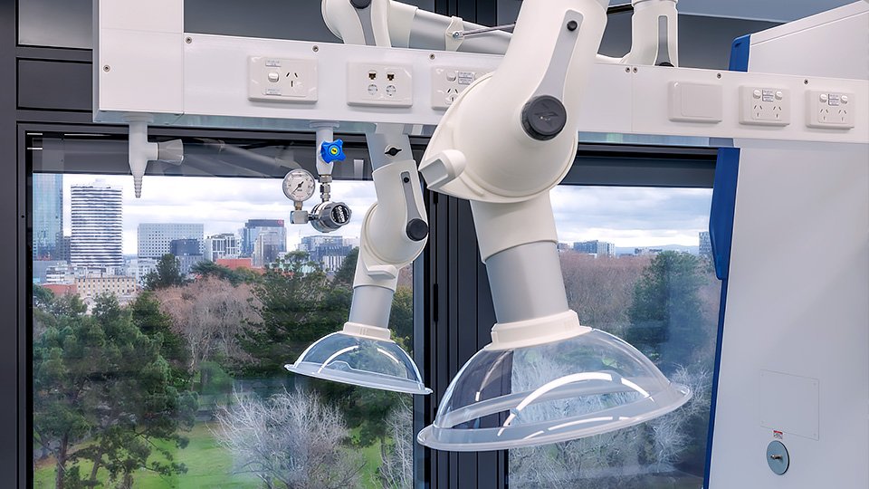 Two articulated local extraction arms mounted beneath overhead service panels