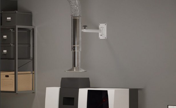 Wall-mounted extraction arm positioned above a machine