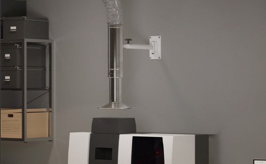 Wall-mounted extraction arm positioned above a machine